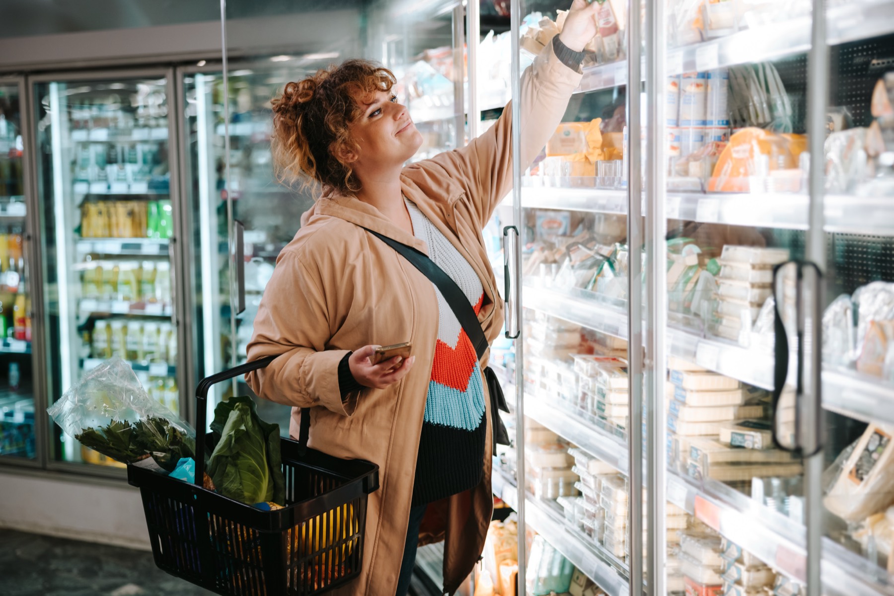 A woman choosing a product from a supermarket chiller
